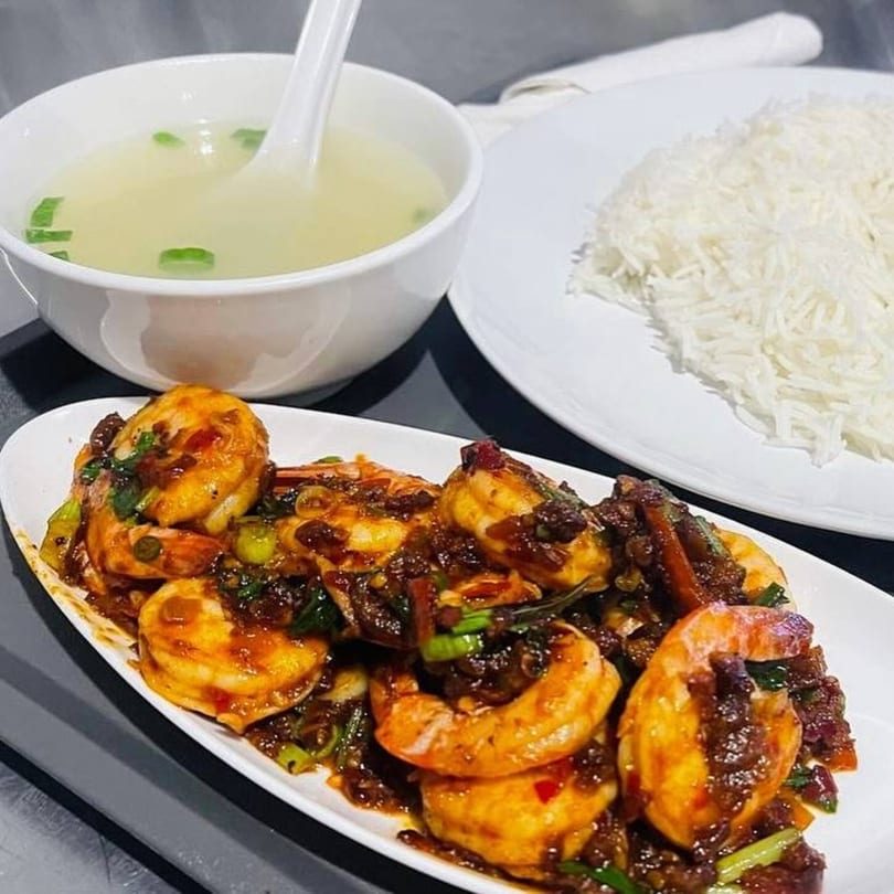 Spicy Asian-fusion shrimp with green onions, served with white rice and a bowl of soup.