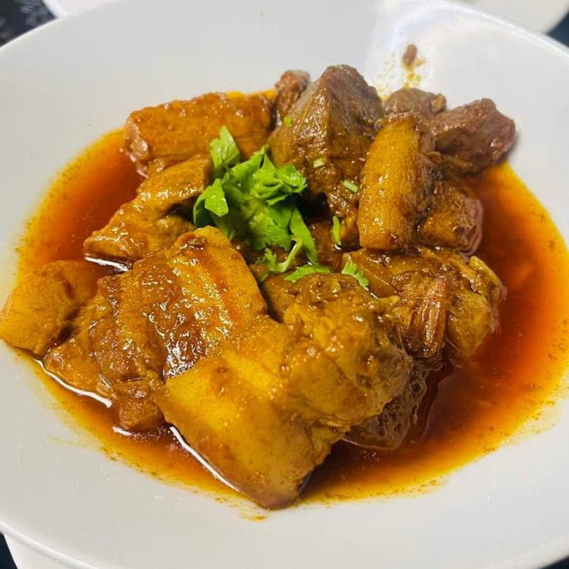 Asian-fusion braised pork belly and potatoes in a rich, savory sauce, garnished with fresh cilantro.