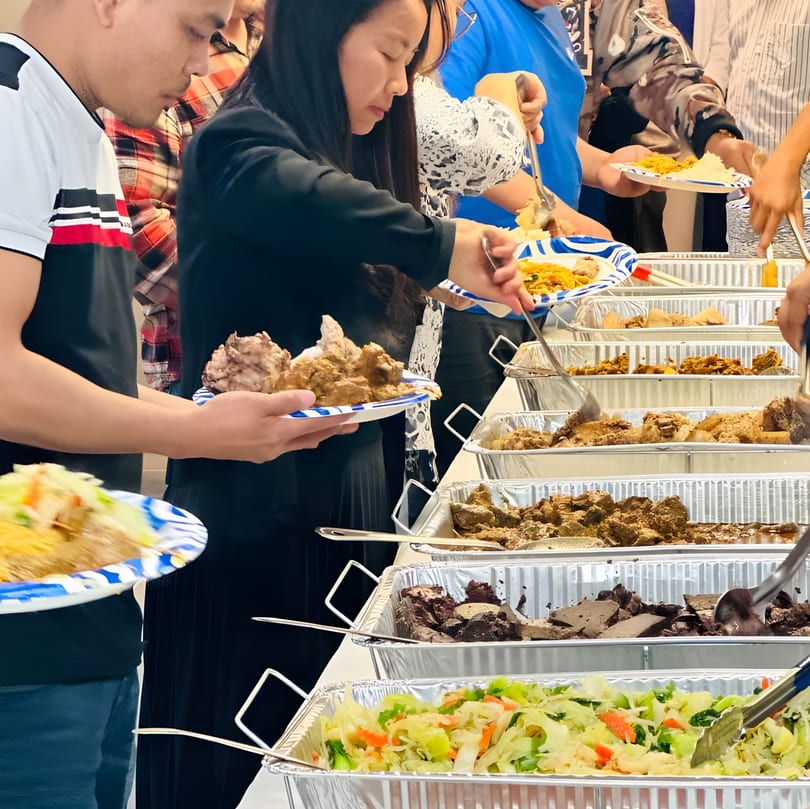 People serving themselves various Asian-fusion dishes from a buffet line at The Corner Restaurant.